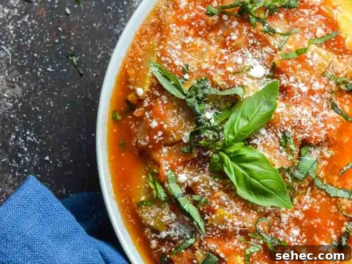 A white bowl with marinara dish of zucchini and fresh basil on top