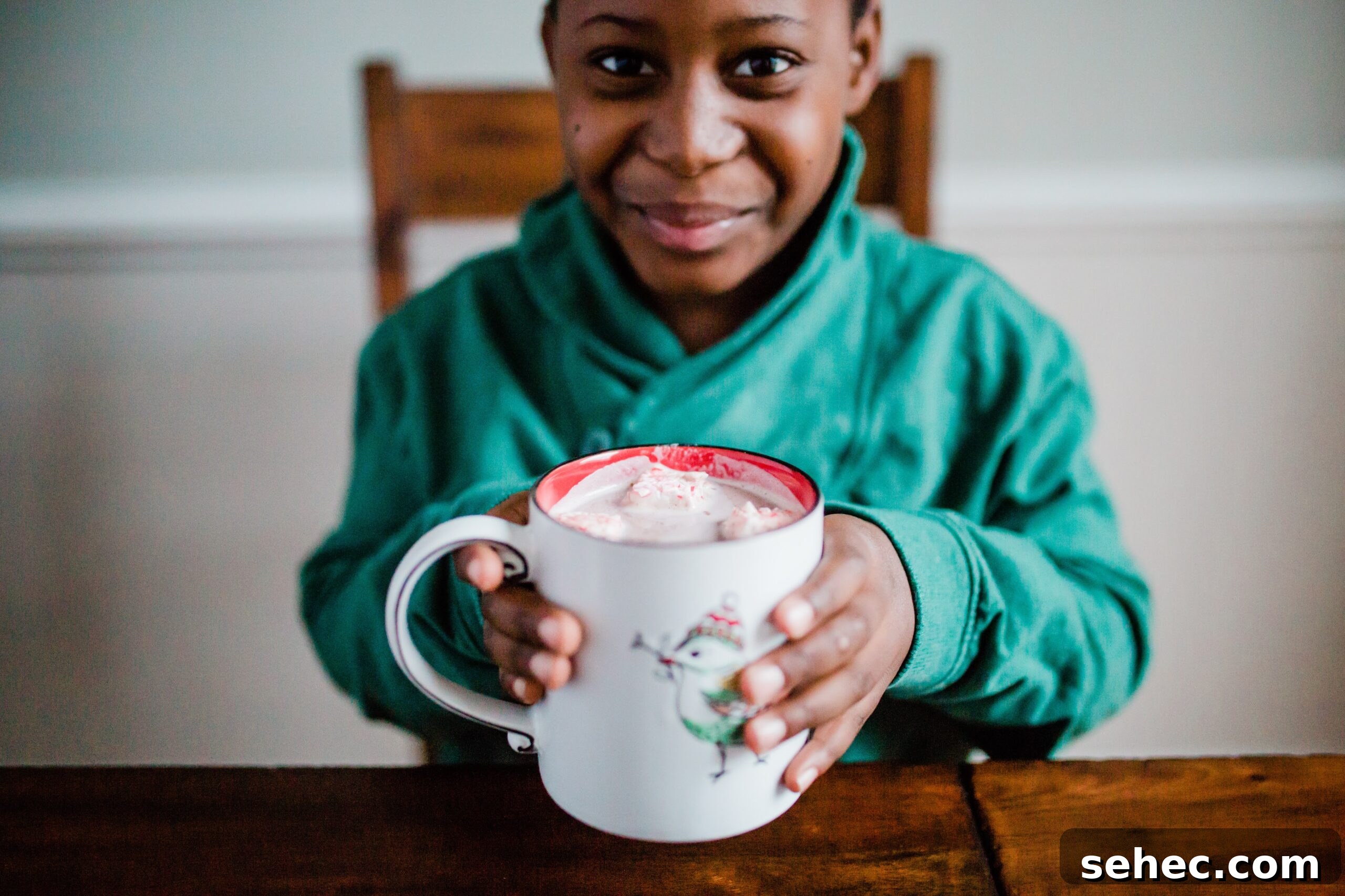 Joshua holding a mug of hot chocolate with peppermint marshmallows.