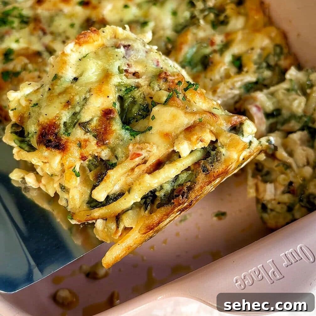Marry Me Chicken Pasta Bake with Creamy Tuscan Sauce 7 A slice of freshly baked pasta bake being lifted from a baking dish. The pasta bake is golden brown with melted cheese on top and visible layers of pasta, vegetables, and sauce. Sprinkled with herbs, the dish looks appetizing and savory.