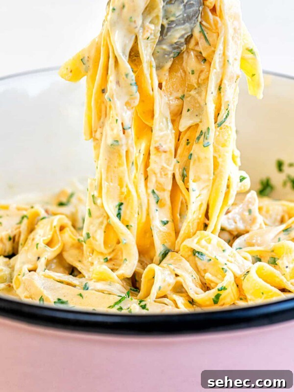 Marry Me Chicken Pasta Bake with Creamy Tuscan Sauce 9 Tongs holding up creamy chicken Alfredo tagliatelle