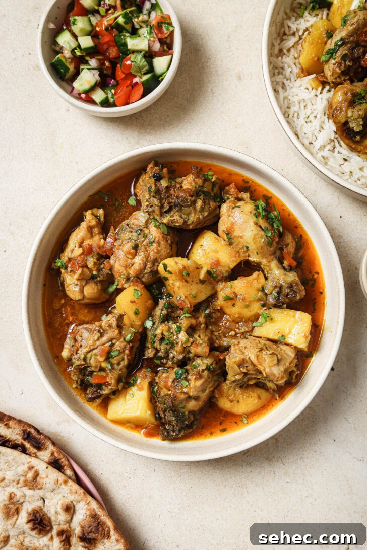 Instant Pot Chicken Curry Recipe 2 Pakistani Chicken Curry in a bowl surrounded by bowl of Kachumber, naan and a bowl iwth rice topped with Chicken Curry.
