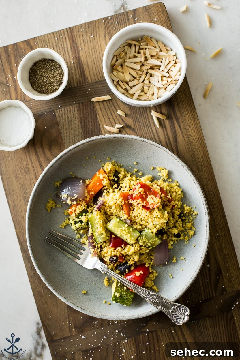 Roasted Vegetable Couscous Recipe 3 Overhead photo of a plate of couscous with vegetables and a small bowl of slivered almonds
