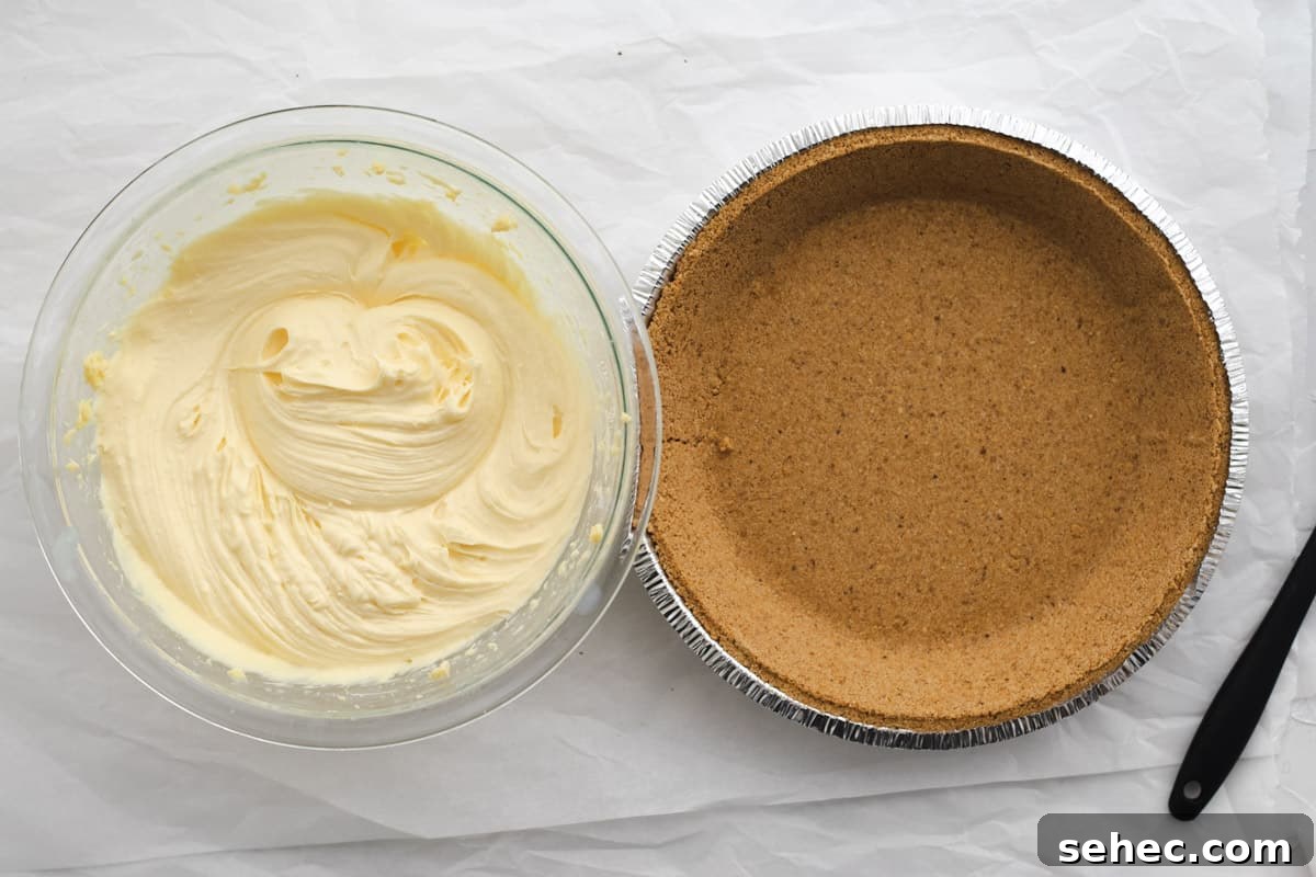 whipped vanilla pudding in a glass bowl next to an empty graham cracker crust in a pie pan