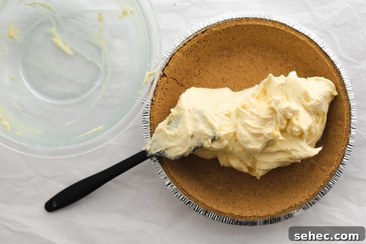vanilla pudding pie filling being added to a graham cracker crust