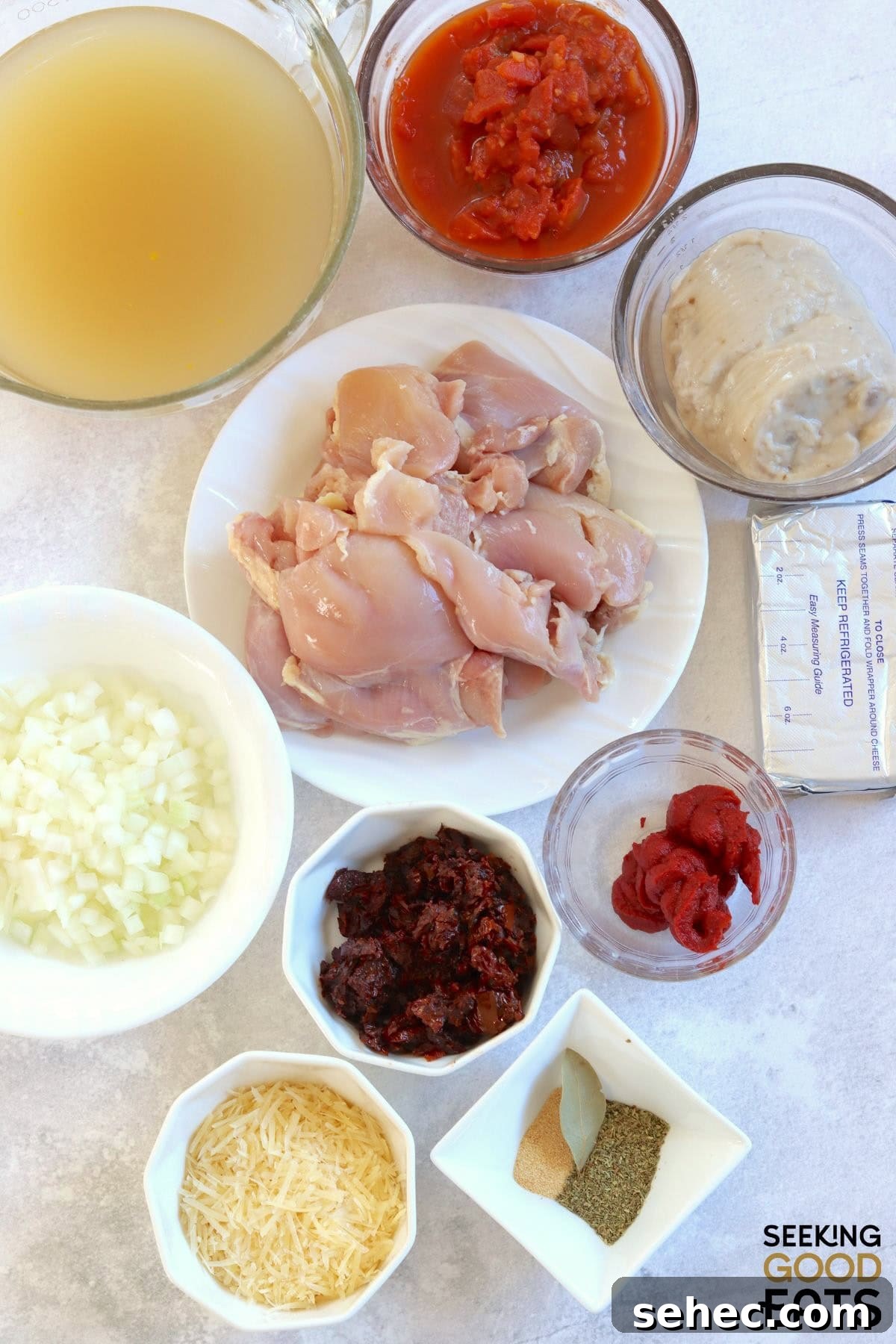 Ingredients needed for making tomato chicken soup on a white board.