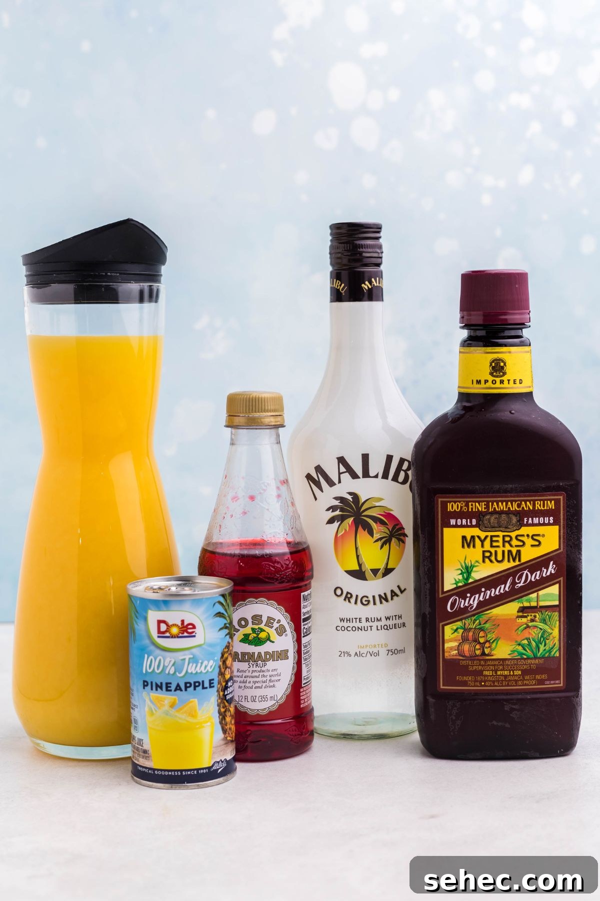 Bahama Mama Cocktail Recipe 3 Bottles of rum, juices, and cocktail ingredients on a marble table.