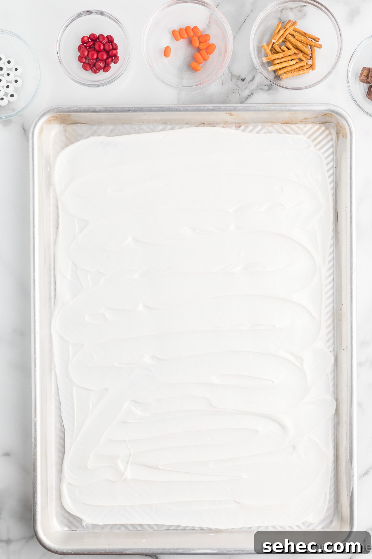 Melted Snowman Chocolate Bark Recipe 5 Melted chocolate spread on a baking sheet.