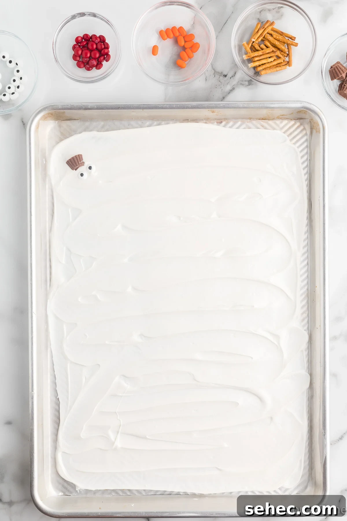 Melted Snowman Chocolate Bark Recipe 6 Peanut butter cups being arranged on melted chocolate.