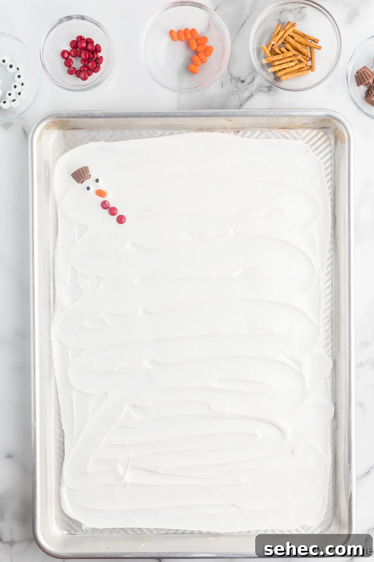 Melted Snowman Chocolate Bark Recipe 7 Candy pieces arranged on a pan.