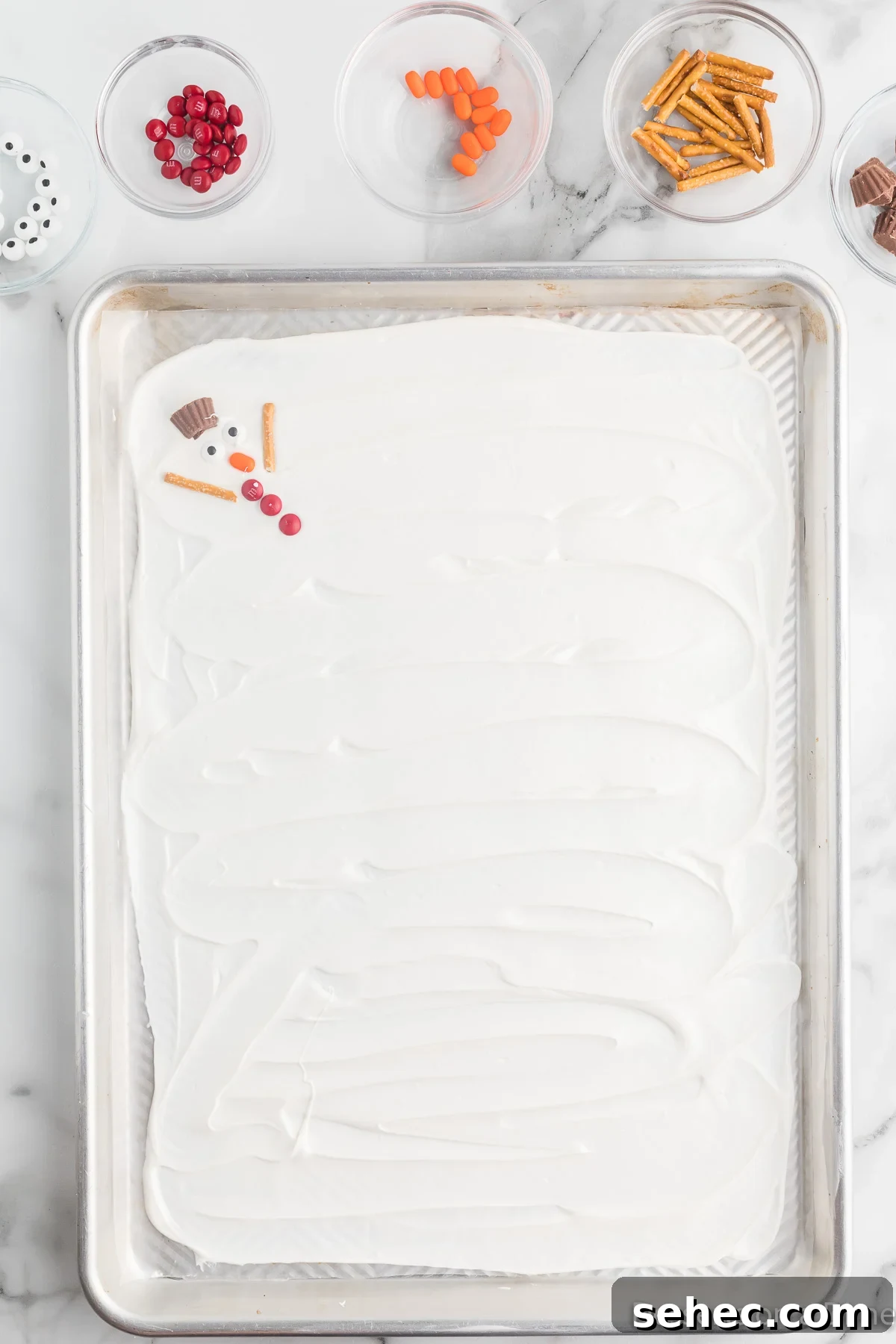 Melted Snowman Chocolate Bark Recipe 8 Pretzel arms arranged around a snowman.