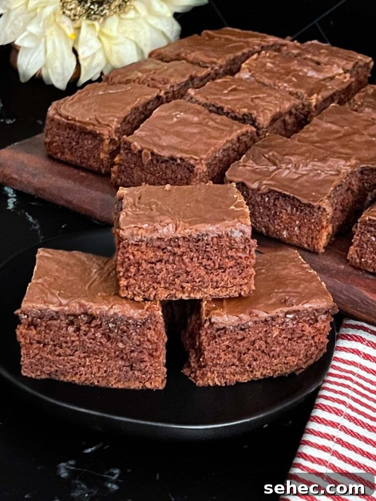 Three buttermilk brownies stacked on a dark plate.