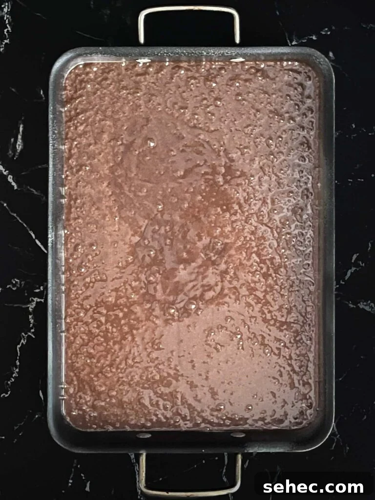 Buttermilk brownie batter poured into the prepared baking pan on a dark surface.