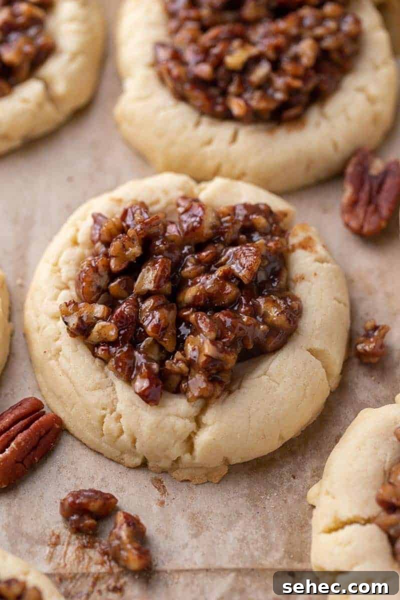 40 Crumbl Cookie Copycat Recipes to Try in 2025 23 Soft Crumbl pecan pie cookies topped with gooey pecan filling on parchment paper
