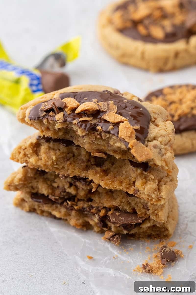 40 Crumbl Cookie Copycat Recipes to Try in 2025 32 Stacked Crumbl Butterfinger peanut butter cookies showing soft chewy center with melted chocolate and crunchy Butterfinger pieces
