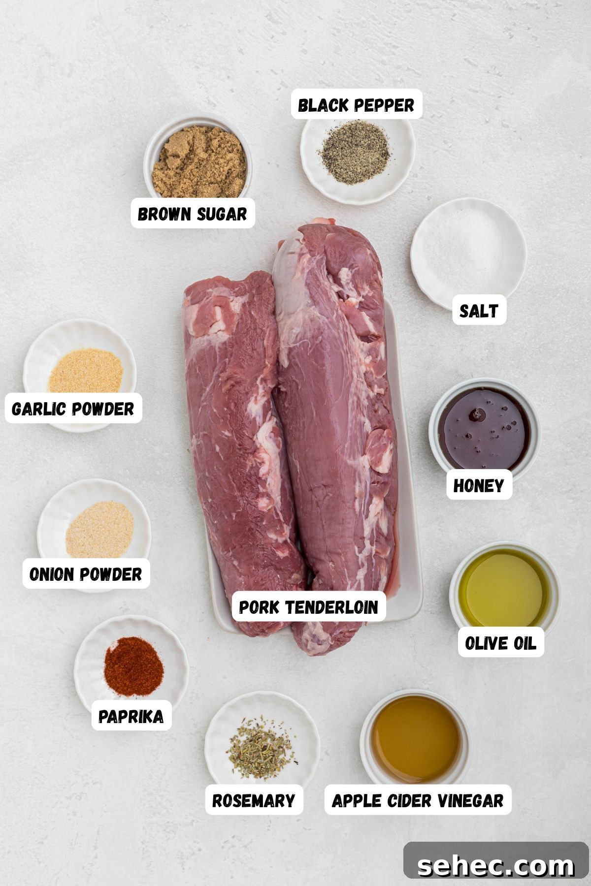 Juicy Smoked Pork Tenderloin Recipe 3 ingredients measured into small bowl and labeled, on a white marble table.