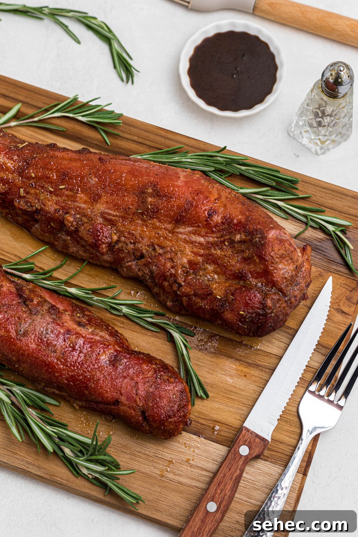 Juicy Smoked Pork Tenderloin Recipe 10 Smoked tenderloins on a wooden cutting board, after having glaze cooked on top and before cutting.