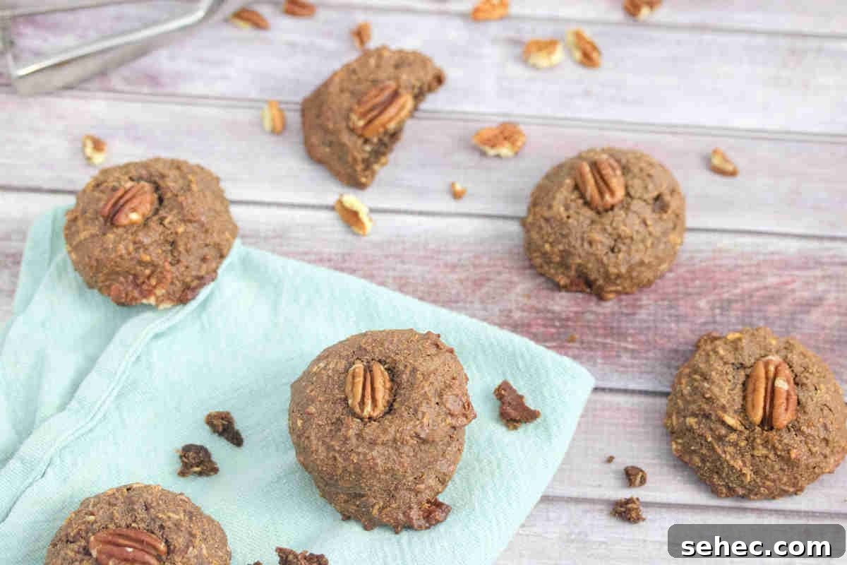 High Protein Cookies for Pregnancy 10 Chocolate pregnancy cookies with pecans on top on a blue linen with pecans around them.