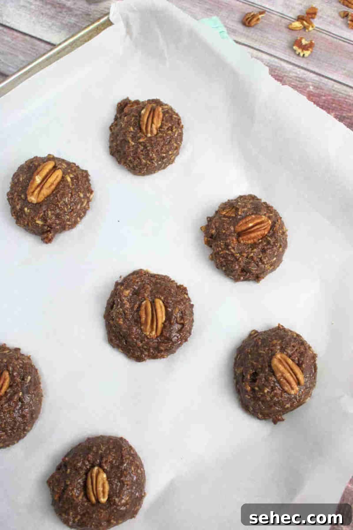 High Protein Cookies for Pregnancy 7 Raw chocolate pregnancy cookies topped with pecans on a baking sheet lined with parchment paper.