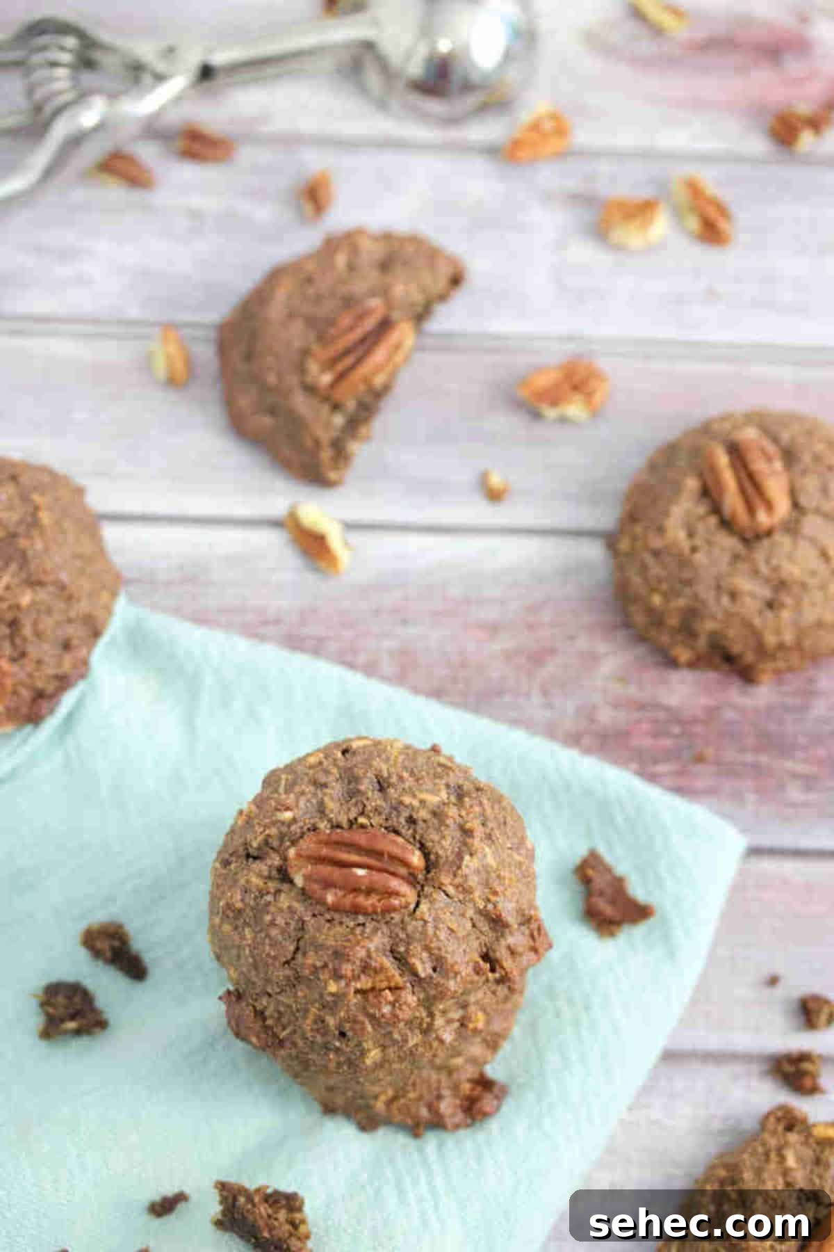High Protein Cookies for Pregnancy 8 Chocolate pregnancy cookies with pecans on top on a blue linen with pecans around them.