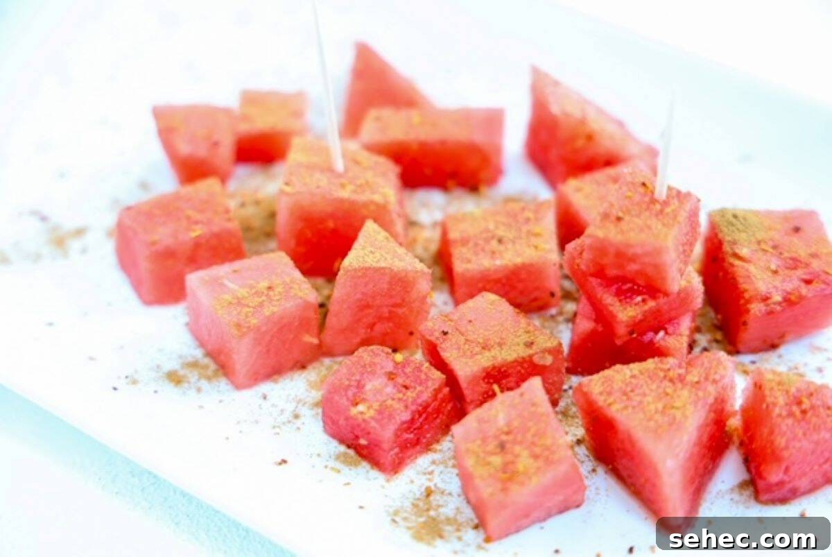 5 Minute Tajin Watermelon Snack 4 Watermelon topped with seasonings on a white plate.