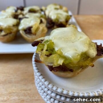 15 Cozy Cold Weather Appetizers for Entertaining 2 Philly Cheesesteak bite on a small stack of dishes with the serving plate in the background.