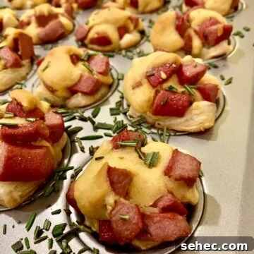 15 Cozy Cold Weather Appetizers for Entertaining 4 Corn dog nuggets in a mini-muffin pan with rosemary sprinkled on top.