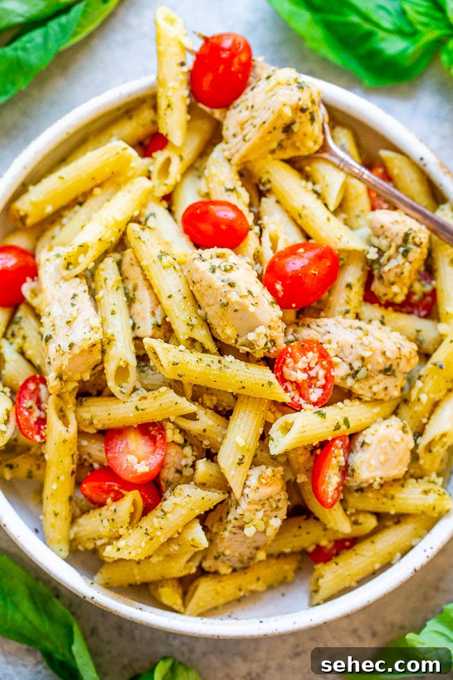 Chicken Asparagus Pasta with Tomatoes 15 A bowl of Pesto Parmesan Chicken and Pasta with a fork holding a piece of chicken.