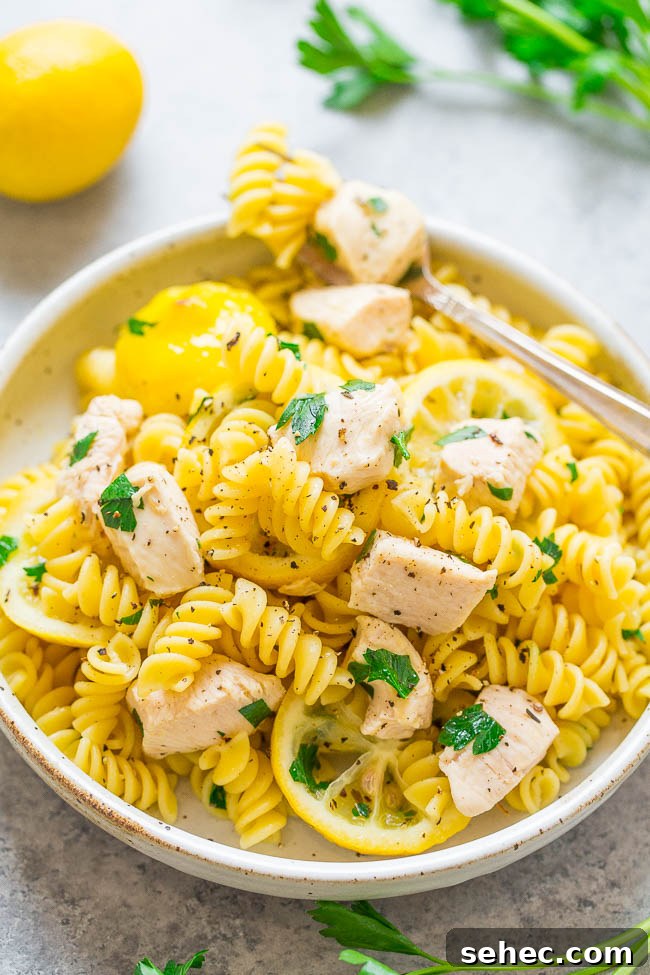 Chicken Asparagus Pasta with Tomatoes 19 A bowl of One-Bag Lemon Chicken and Pasta with a fork on top holding a bite.