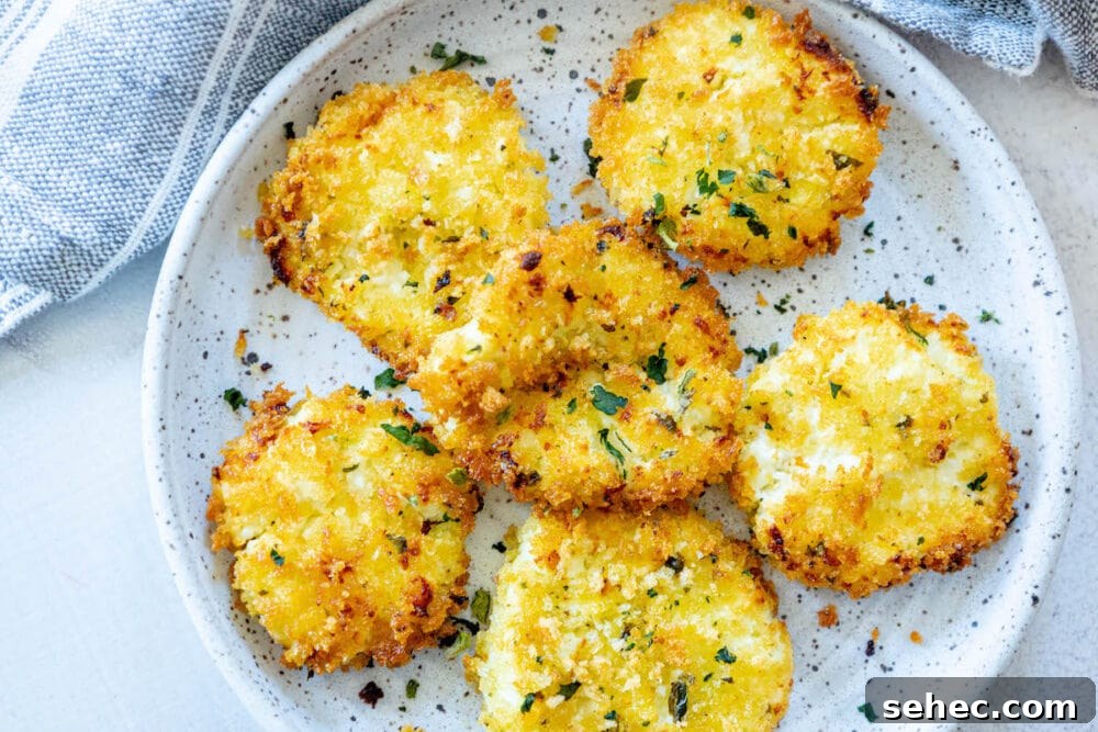 Crispy Baked Goat Cheese Balls Recipe 12 golden baked breaded goat cheese balls topped with herbs on a white speckled plate