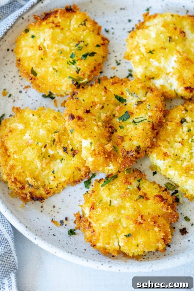 Crispy Baked Goat Cheese Balls Recipe 3 golden baked breaded goat cheese balls topped with herbs on a white speckled plate