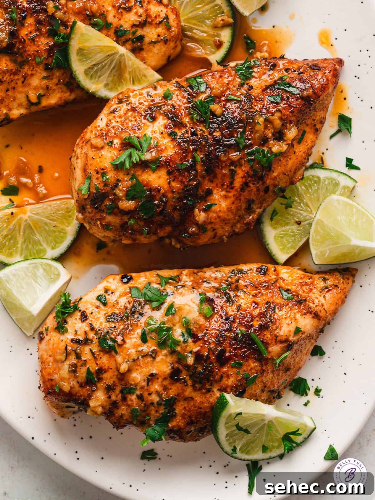 Easy Garlic Lime Chicken Two chili lime chicken breasts on a white platter with pieces of fresh lime.