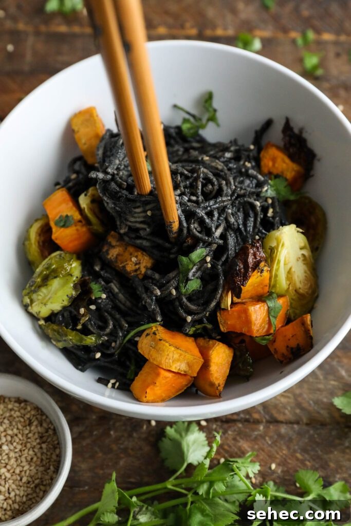 Black Sesame Noodle Bowl with Crunchy Vegetables 12 Black Sesame Noodle Bowl served in bowl topped with cilantro and sesame seeds with chopsticks