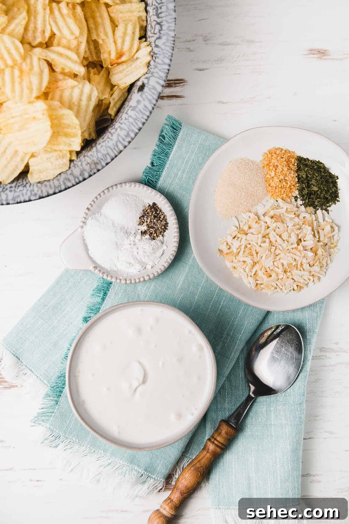 Gluten Free French Onion Chip Dip Recipe 3 Dried spices for gluten-free onion soup mix measured out on small plates. A bowl of sour cream on a teal napkin.