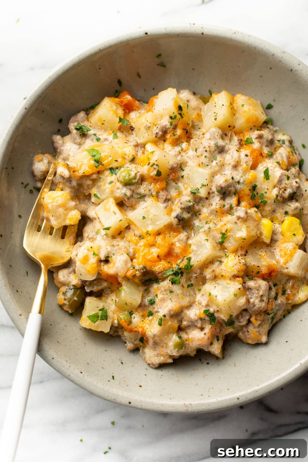 Cheesy Ground Beef Potato Casserole 7 a bowl with a serving of ground beef and potato casserole with a fork