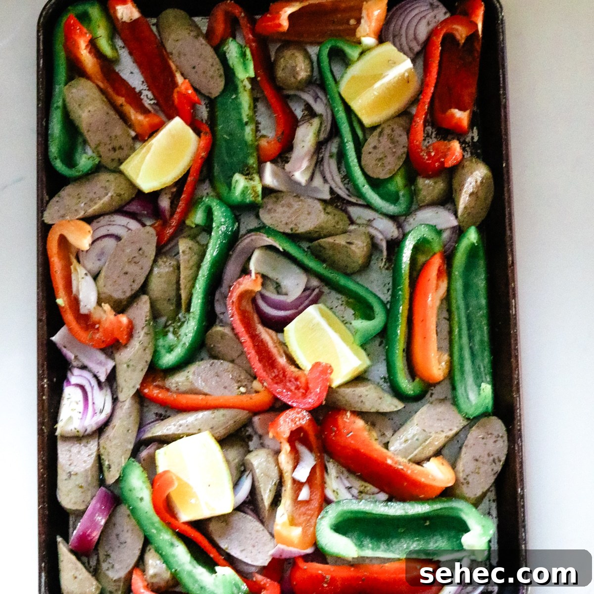 Oven Baked Sausage and Peppers Recipe 7 Seasoned sausage and peppers on a baking sheet.