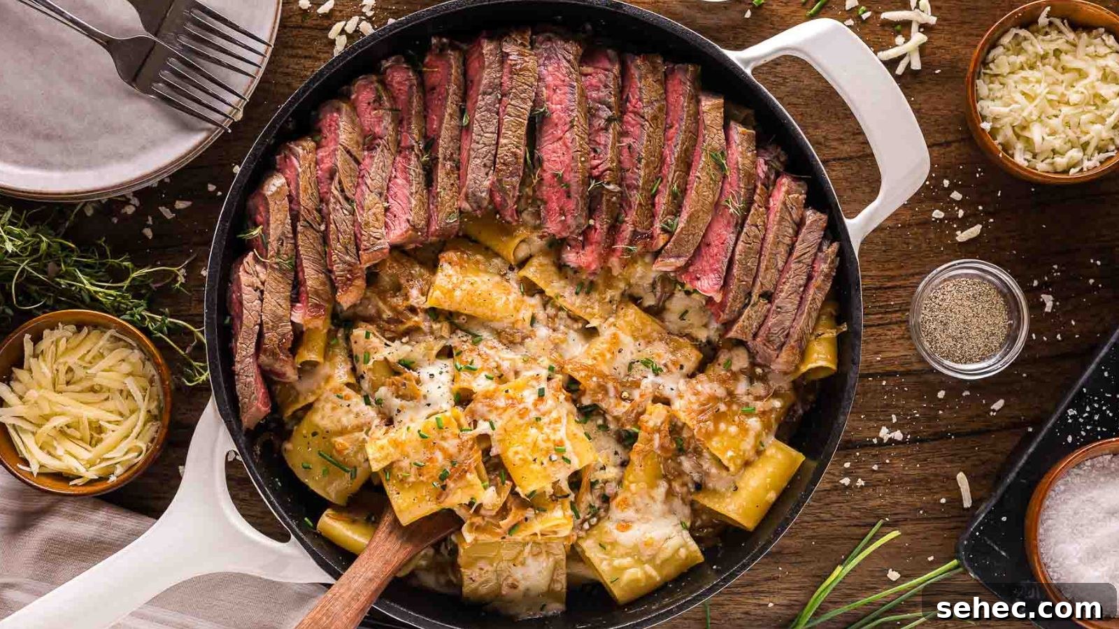Creamy French onion pasta topped with sliced steak and caramelized onions in a deep bowl.