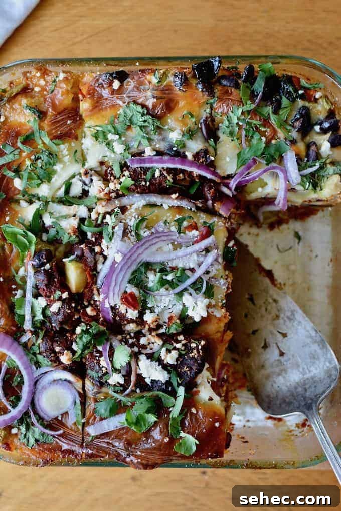 Over 35 Recipes Using Canned Chipotle Peppers in Adobo 6 An overhead image of a deep dish black bean enchilada casserole with two slices taken out and a metal serving utensil in the space.