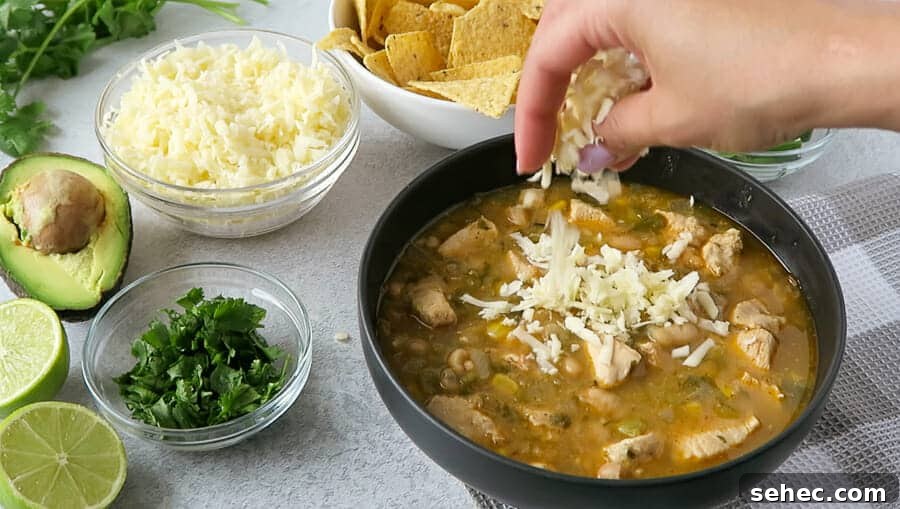 Dairy Free Instant Pot White Chicken Chili 8 monterey jack cheese being sprinkled on a bowl of Instant Pot White Chicken Chili (Dairy-free)