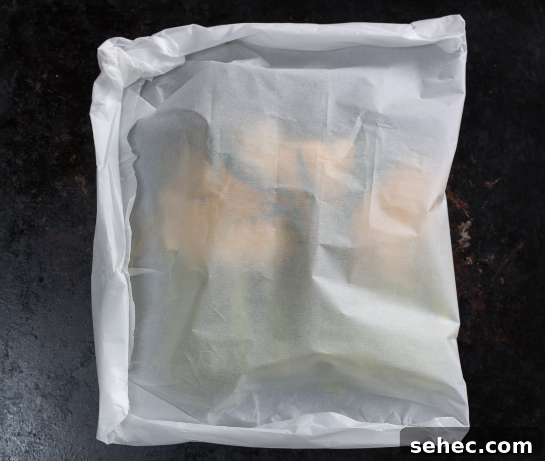 Spring Asparagus Pasta Baked in Parchment 7 Folded parchment packet crimped and ready for baking on a rimmed tray