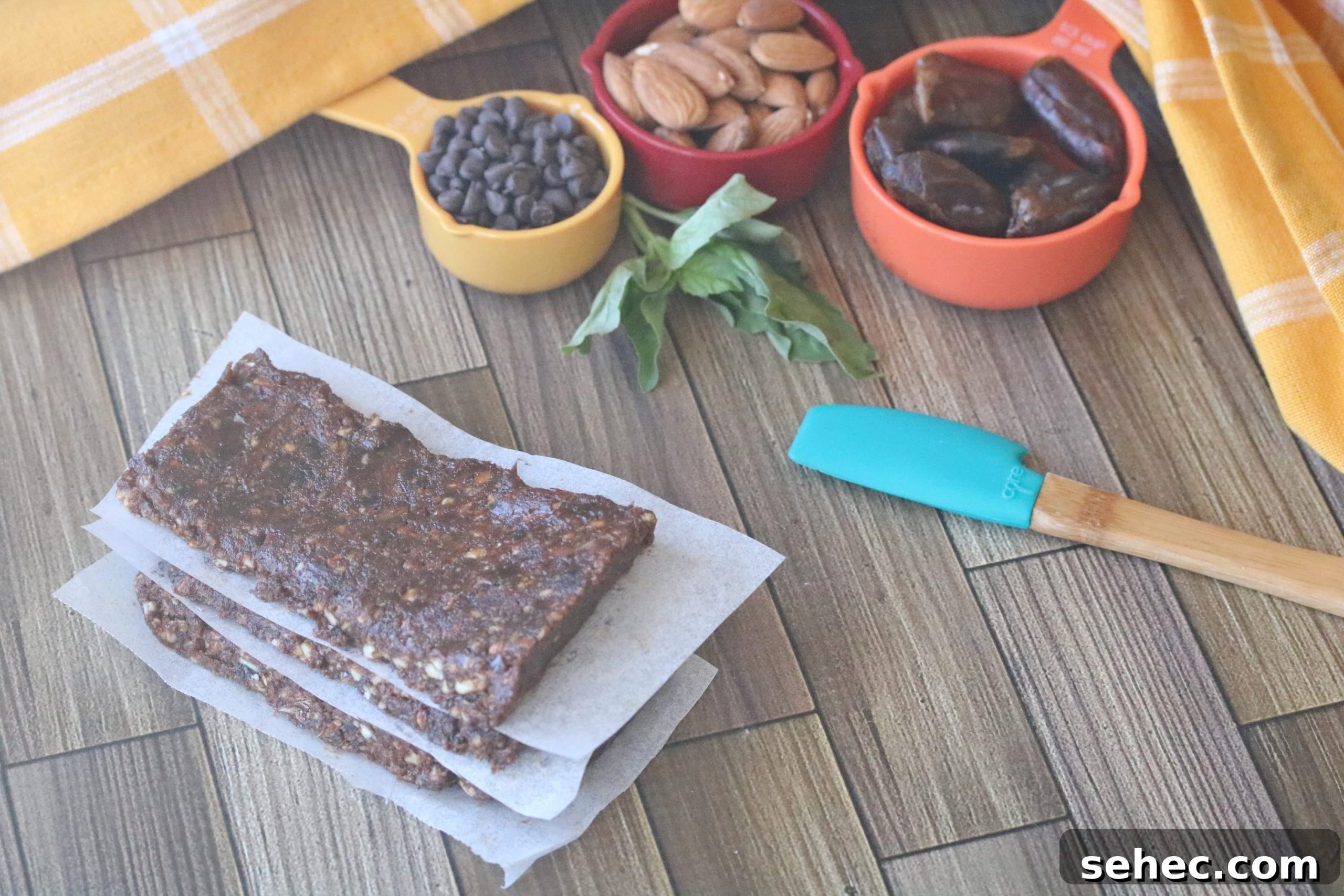 Dairy Free Chocolate Mint Protein Bars Recipe 14 Three chocolate protein bars stacked on parchment paper with ingredients behind them