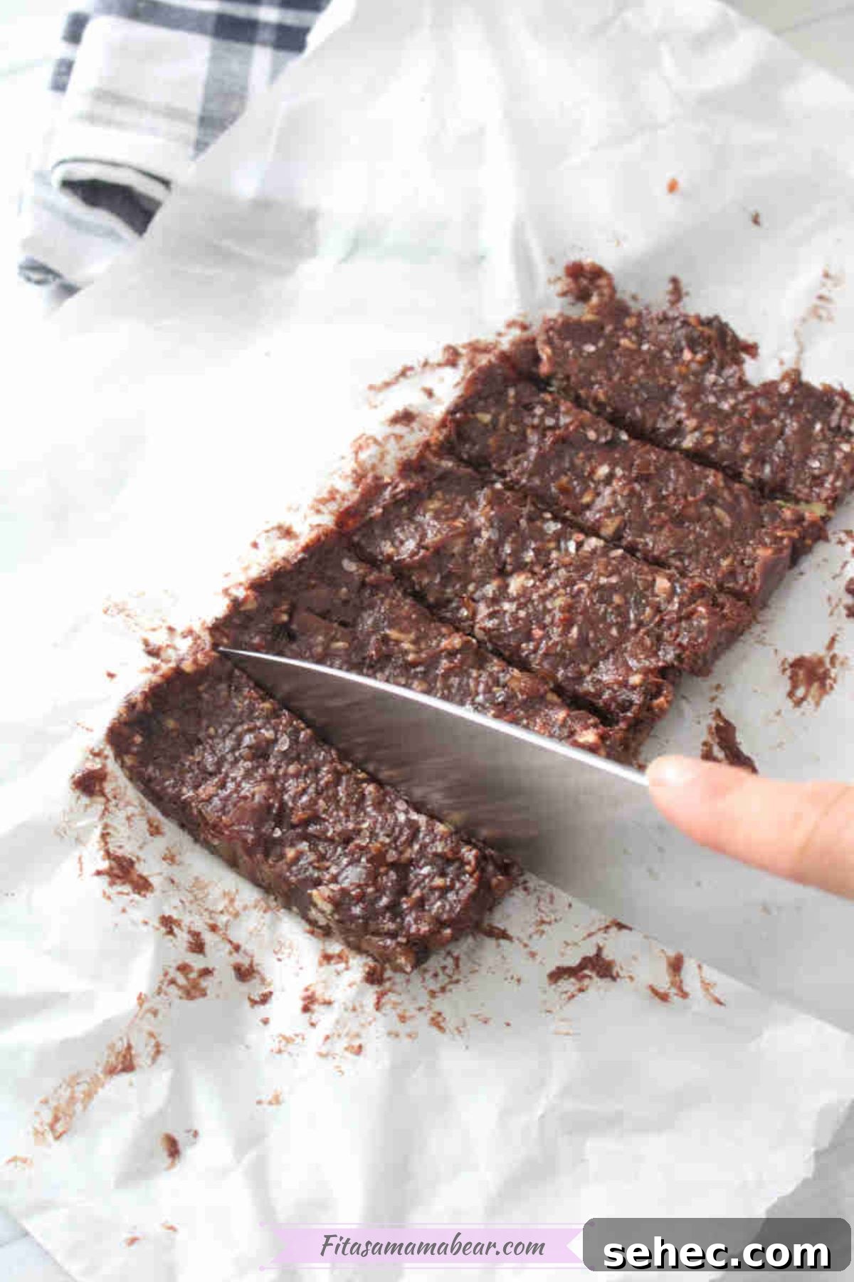 Dairy Free Chocolate Mint Protein Bars Recipe 7 Chocolate date protein bars on parchment paper being sliced.