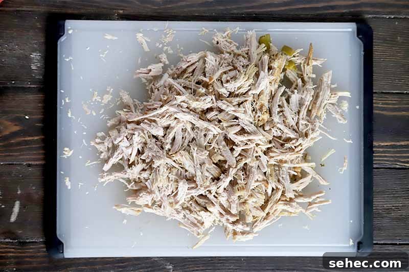 Slow Cooker Pork Tacos for Taco Tuesday 10 Horizontal image of shredded cooked meat on a white cutting board.