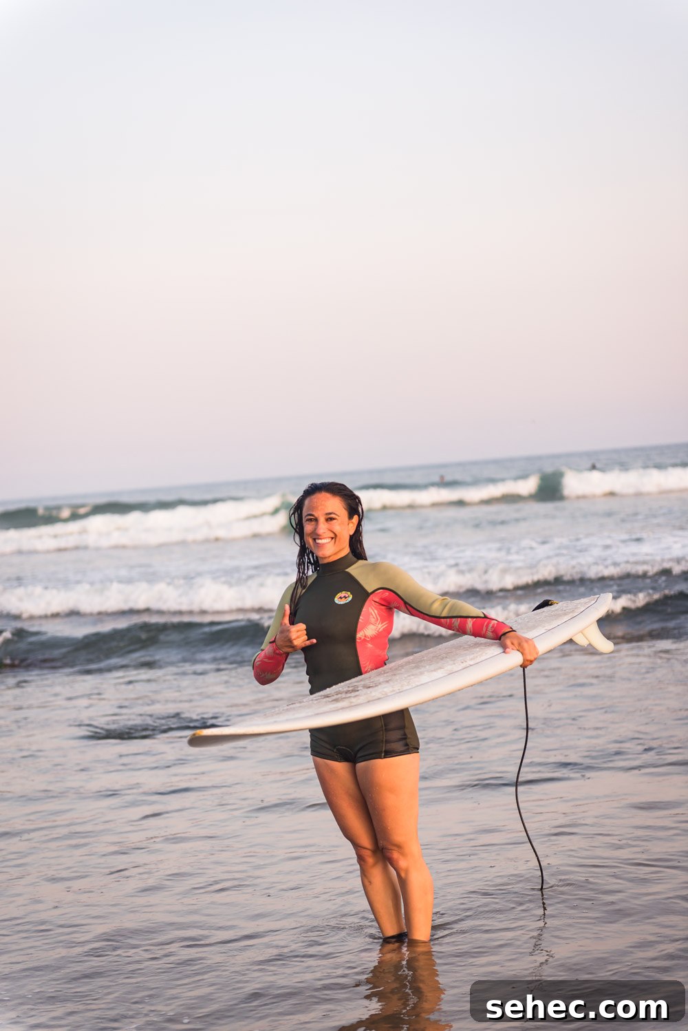 Ditch Plains Surf Guide Waves Tides and Local Tips 14 Chef Daniela Gerson, post surf session, in her wetsuit giving a shaka to the camera.