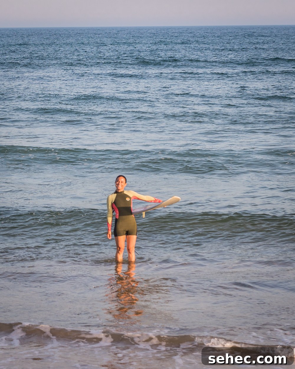 Ditch Plains Surf Guide Waves Tides and Local Tips 3 Chef Daniela Gerson in a wetsuit in the ocean with her surfboard in Ditch Plains, NY.
