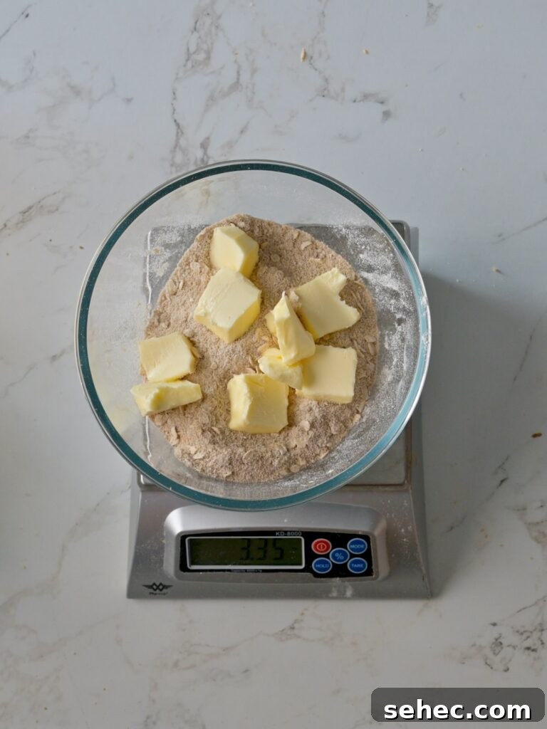 Moist Applesauce Crumb Cake with Cinnamon Streusel 14 Cubes of butter sitting on top of a bowl of flour, sugar, and cinnamon mixture, ready to be mixed into a crumb topping.