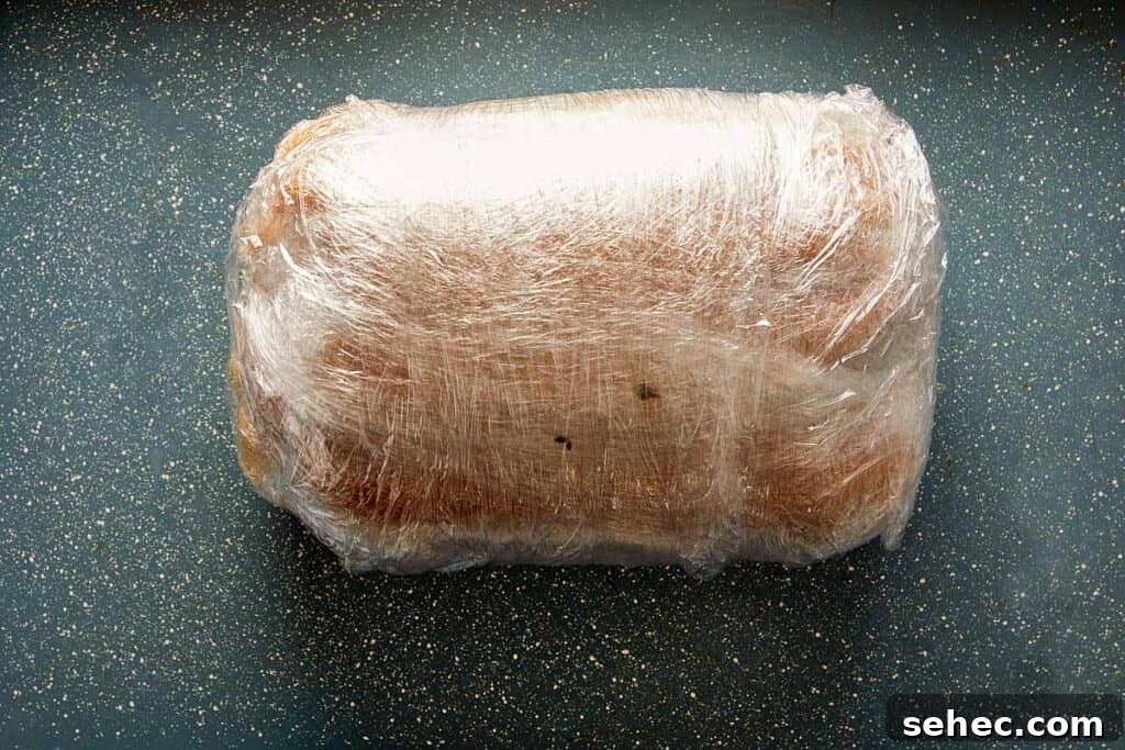 Truffle Beef Wellington Recipe with Red Wine Sauce 12 wrapped meat on plastic on a pan