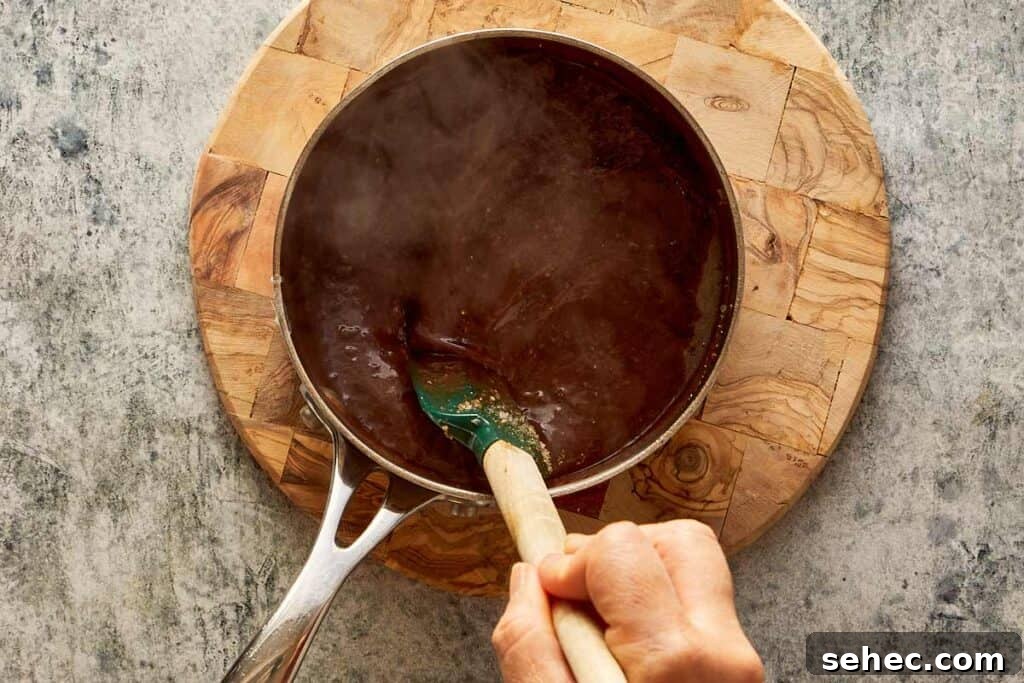 Truffle Beef Wellington Recipe with Red Wine Sauce 18 steaming bowl of brown liquid on top of a wooden board