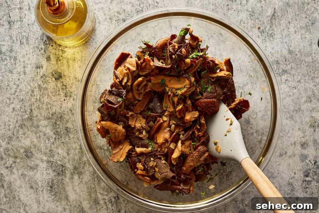 Truffle Beef Wellington Recipe with Red Wine Sauce 6 bowl of chopped mushroom mix being mixed with a wooden spoon.
