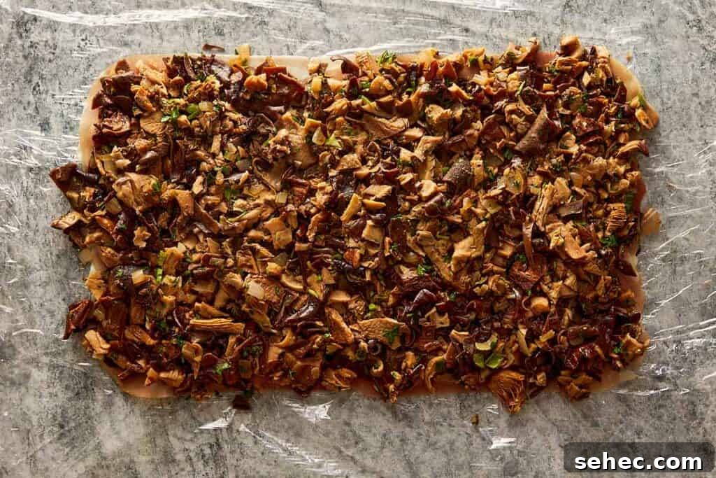 Truffle Beef Wellington Recipe with Red Wine Sauce 10 chopped mushrooms layed down on the plastic wrap in a rectangle