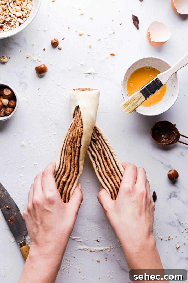 Nutella Babka Recipe: Chocolate-Hazelnut Swirl Loaf 10 overhead view of a person twisting the nutella babka dough